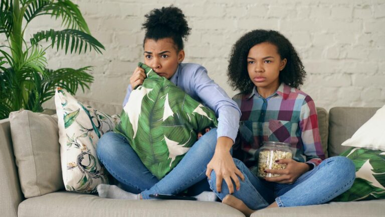 Teenagers watching movie couch popcorn remote control